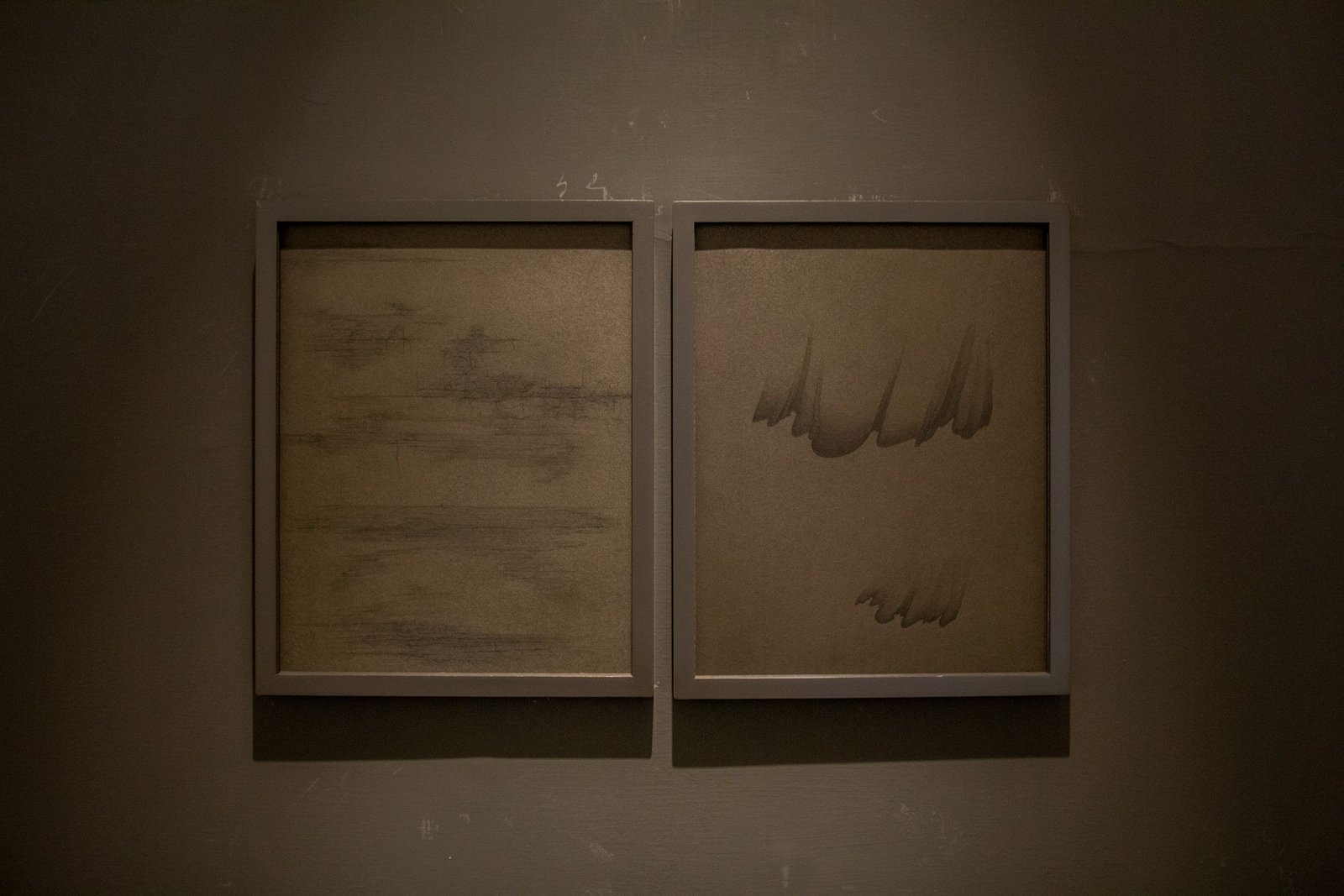 Two framed works with calligraphy hung side by side on a dark gallery wall