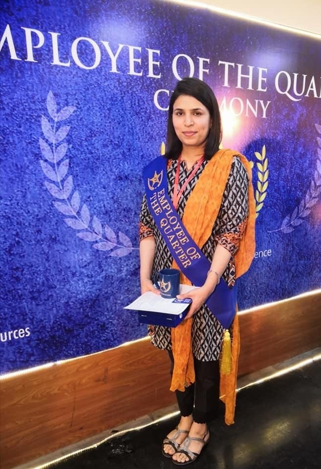Amna Manzoor wearing the Employee of the Quarter sash at UMT