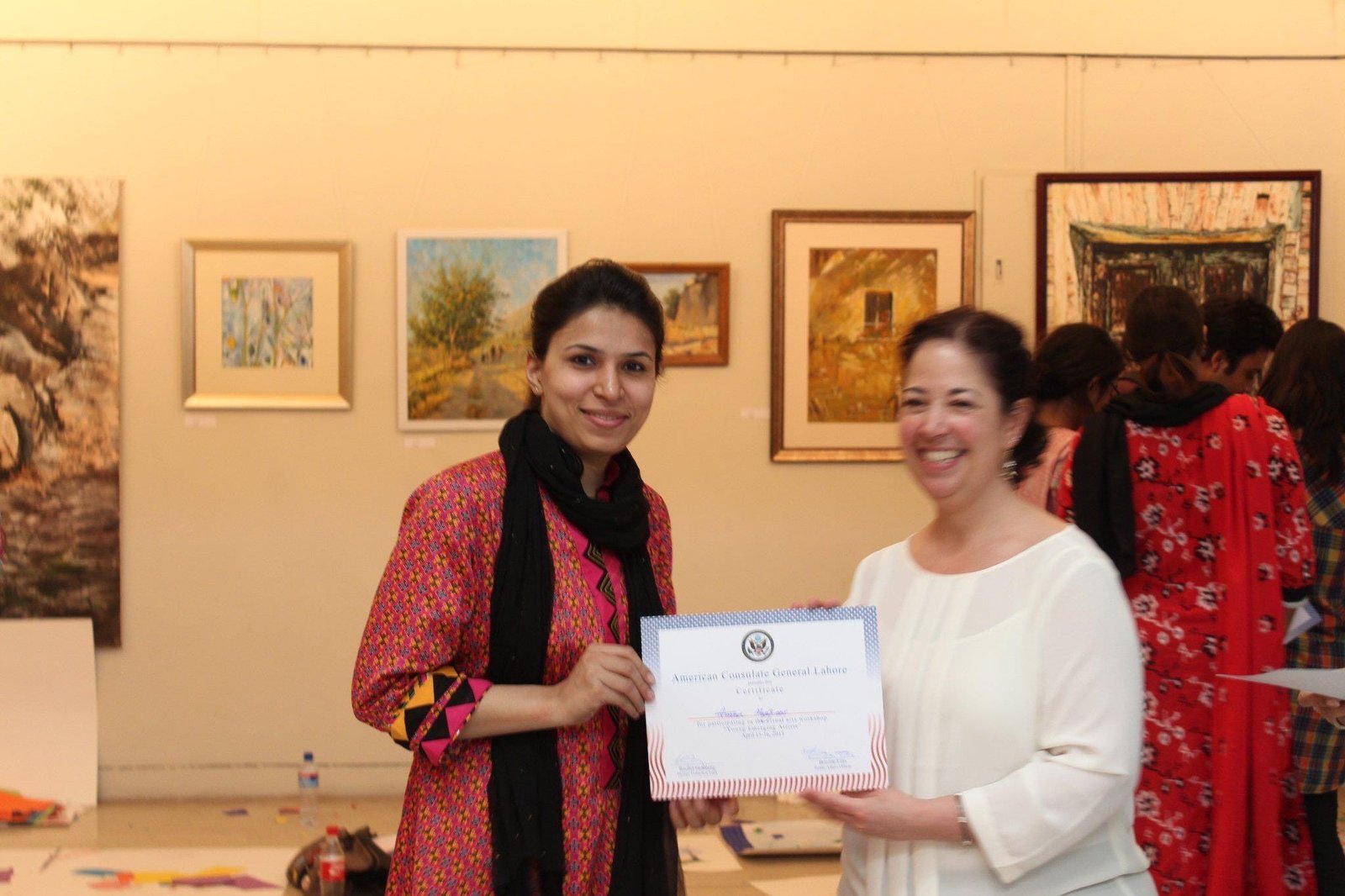 Amna Manzoor holding her workshop certificate in a gallery